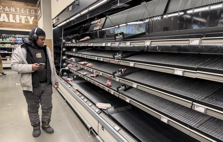 People shop at a supermarket as shelves are left empty