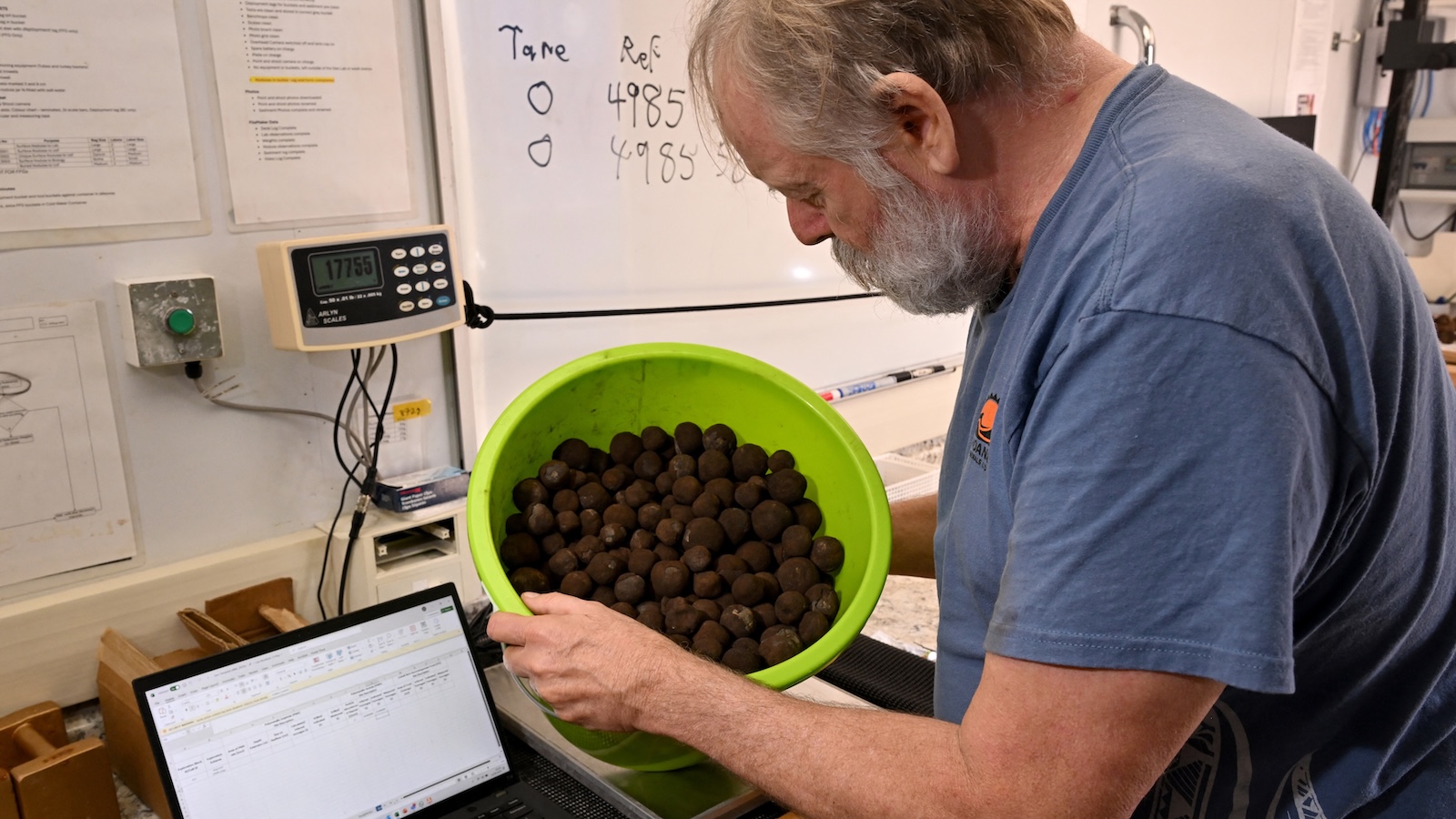 A geologist inspects a bucket of polymetallic nodules, misshapen black globes encrusted with metals like <span class='tooltipsall tooltipsincontent classtoolTips10'>cobalt</span>, <span class='tooltipsall tooltipsincontent classtoolTips9'>nickel</span> and manganese.