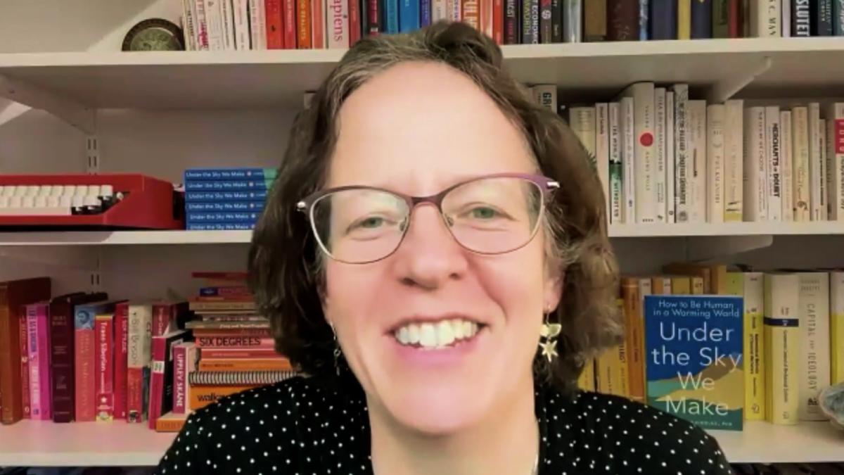 A photo of author Kimberly Nicholas smiling in front of a book shelf