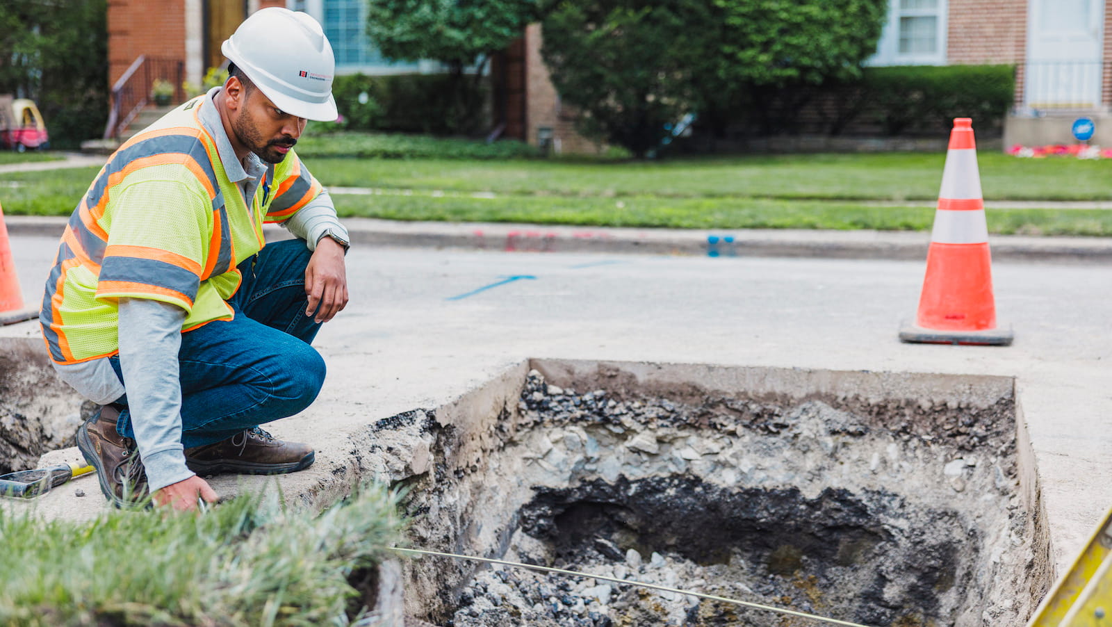 Engineer stands over hole in street where a lead pipe is being replaced.