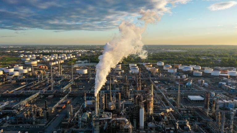 A huge industrial complex sprawls and a smokestack belches smoke