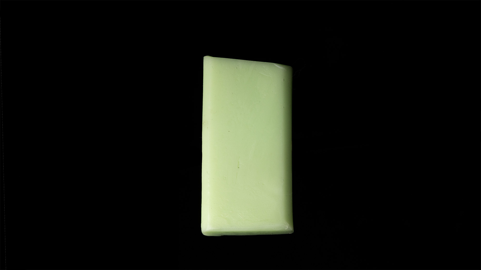 A green slab of fluorinated ski wax lit in a studio setting