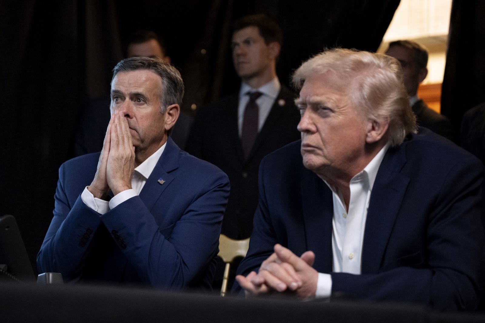 A photo of president Donald Trump and a man tensely watching something off camera