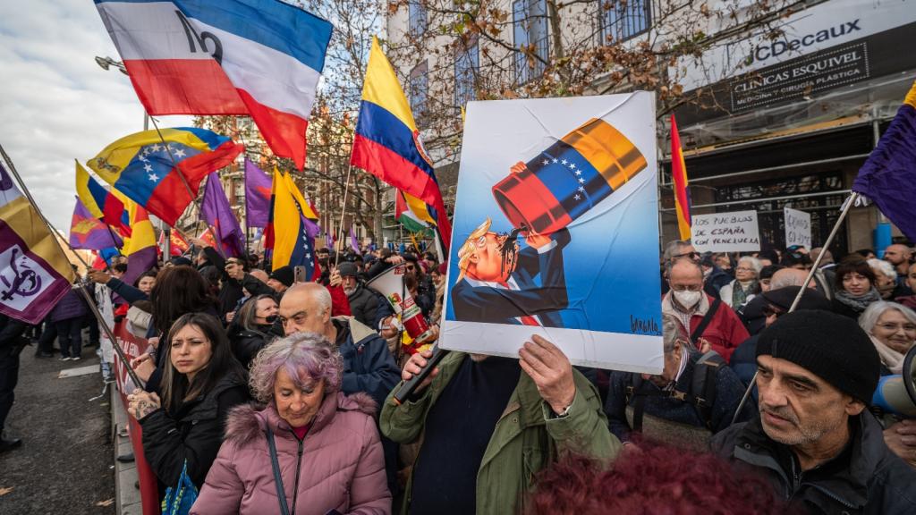 A man holds a placard showing President Donald Trump drinking from a barrel of oil during a protest outside the American embassy in Madrid. Trump has justified his abduction of Venezuelan leader Nicolás Maduro by claiming the United States will help tap Venezuela's oil reserves.