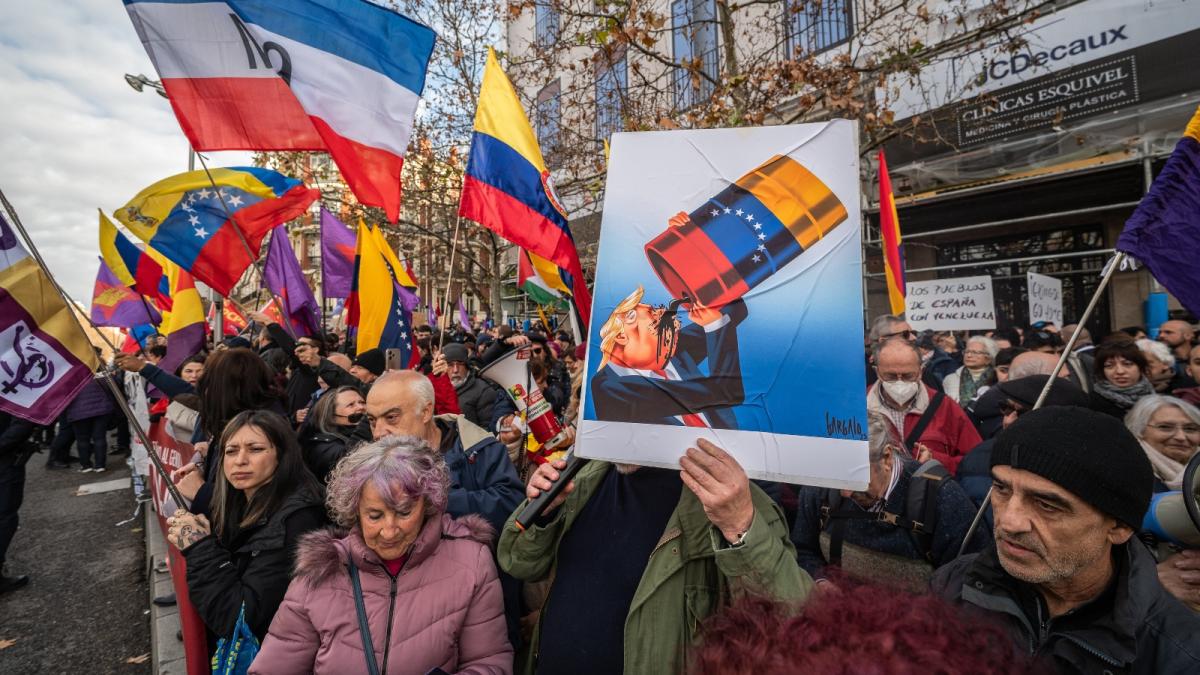 A man holds a placard showing President Donald Trump drinking from a barrel of oil during a protest outside the American embassy in Madrid. Trump has justified his abduction of Venezuelan leader Nicolás Maduro by claiming the United States will help tap Venezuela's oil reserves.
