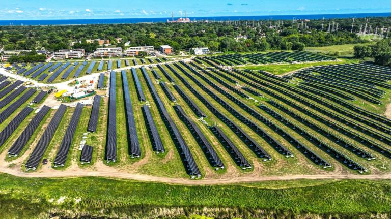 A drone view of rows of solar panels on a green field