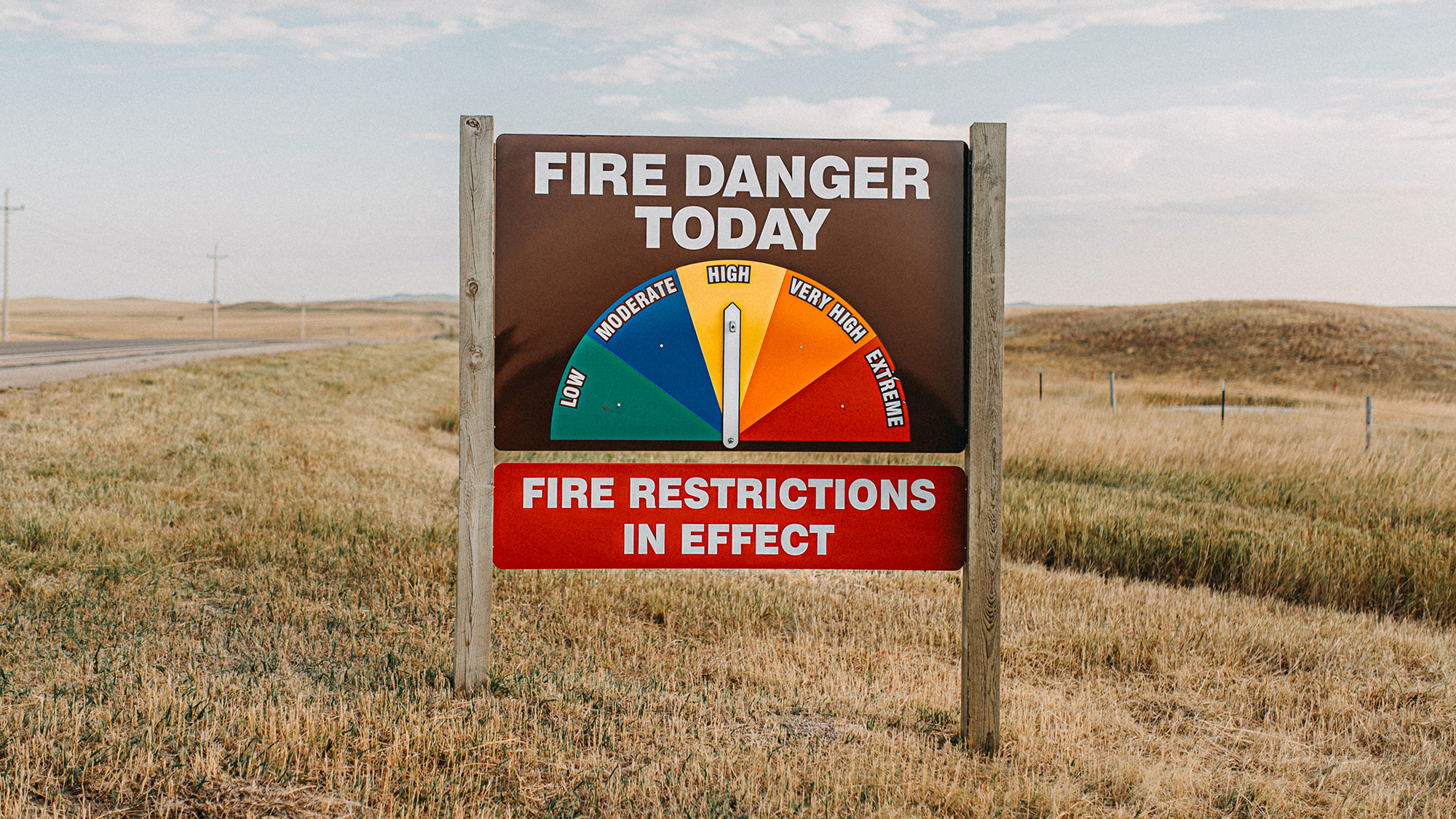 fire danger sign with arrow pointing to "high" fire danger stating that fire restrictions are in effect