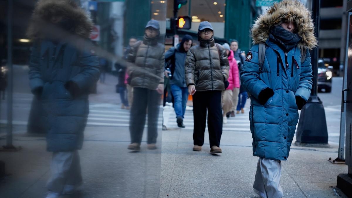 Commuters on a street in downtown Boston brace against the morning cold as a winter storm envelops 230 million Americans.