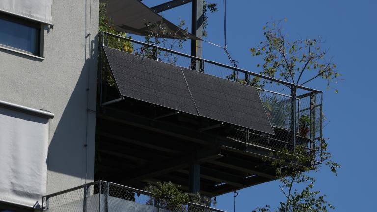 A solar panel sits on the outside of an apartment balcony