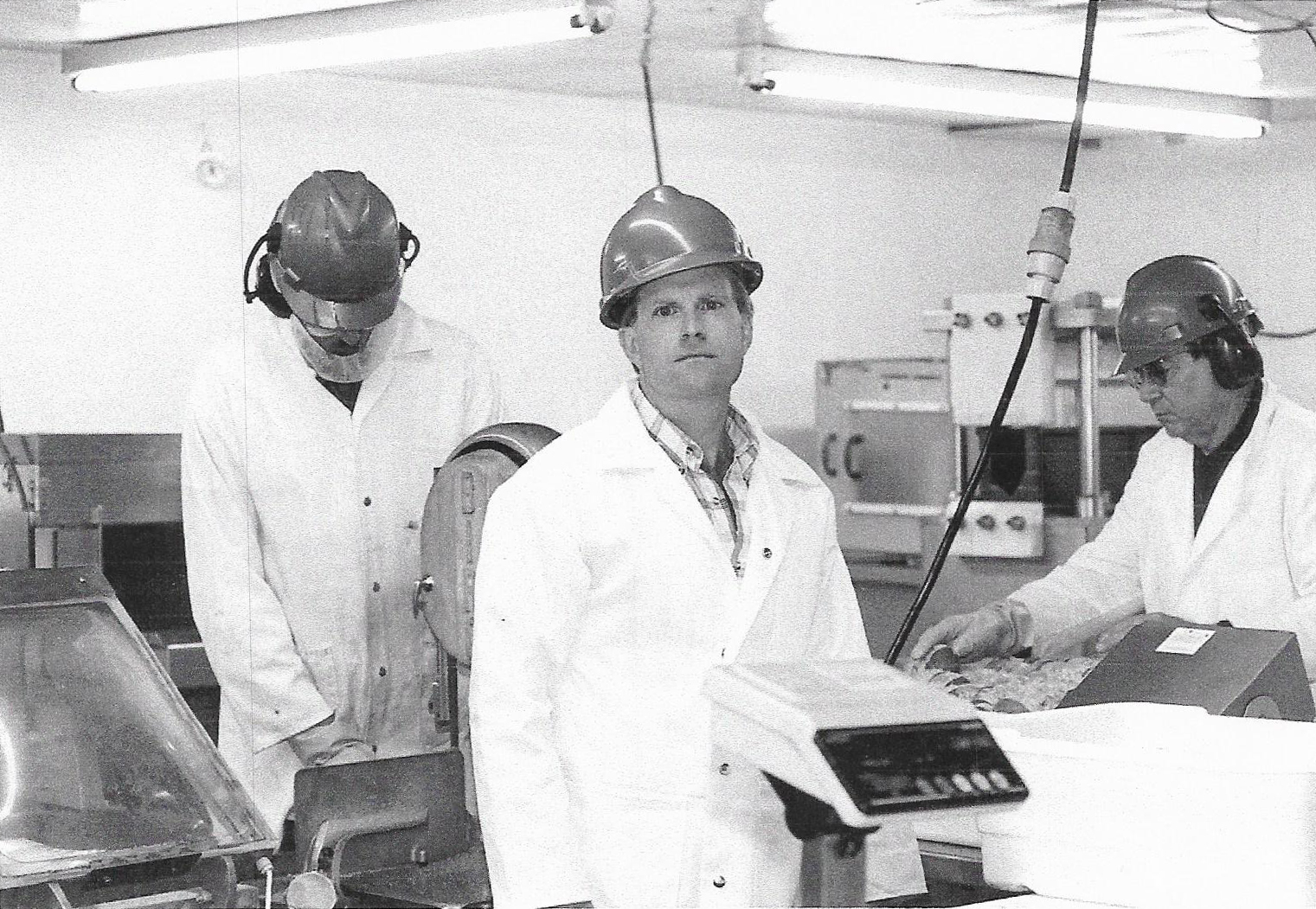Sam Cobb holds a scale in the RMS Foods factory while two men work behind him