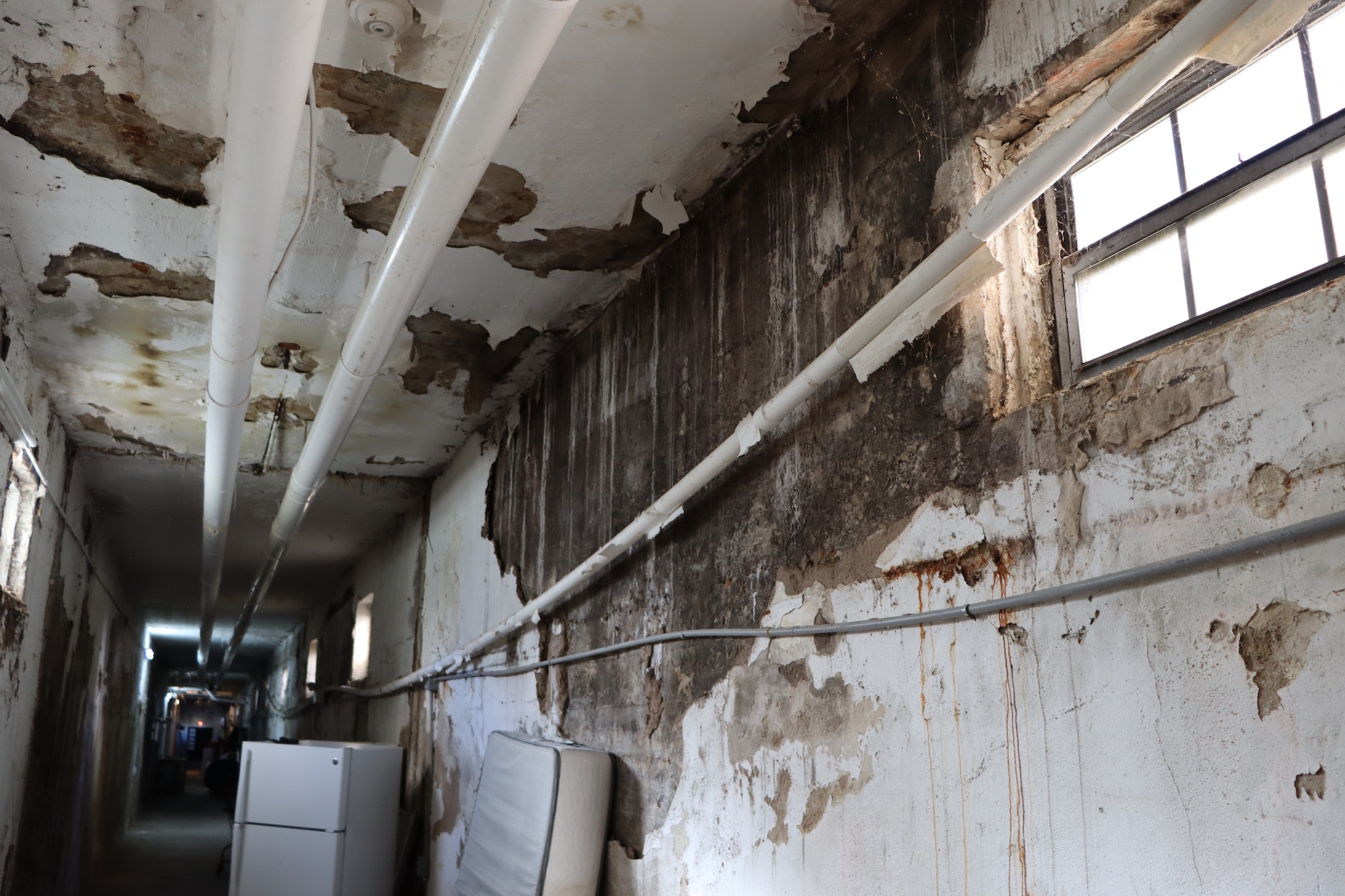 pipes run along the ceiling in a severely damaged building with water damage