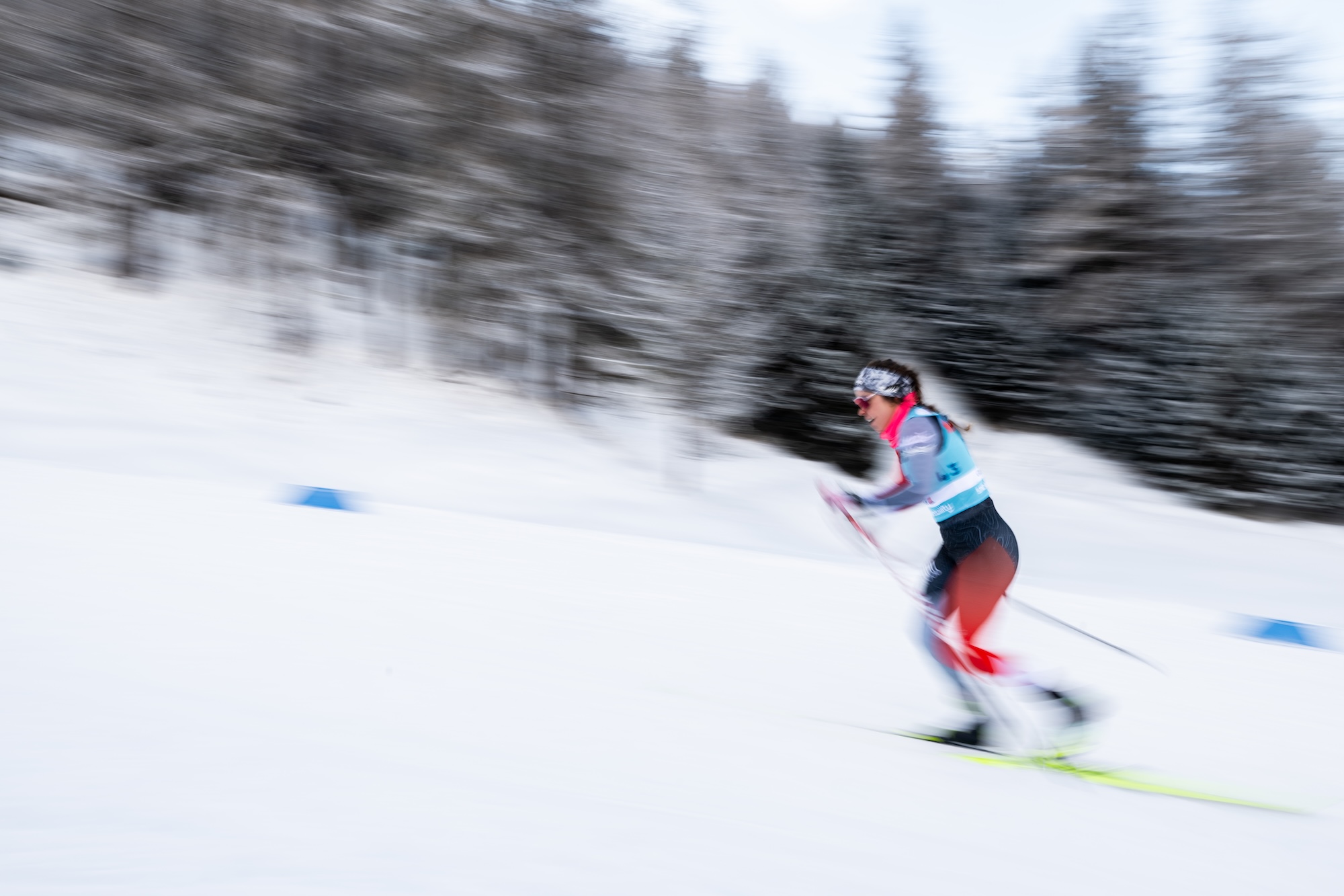 A woman cross contry skis over snowy terrain with a motion blur