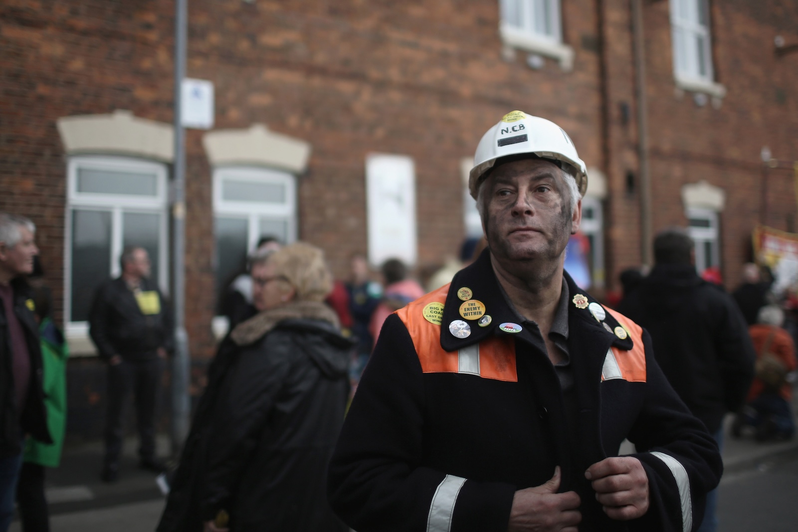 A man in mining gear looks wistfully into the distance in the middle of a march