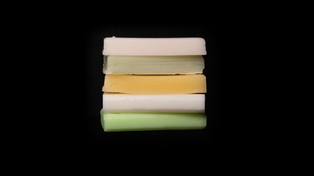 A stack of fluorinated ski waxes sits in front of a black background