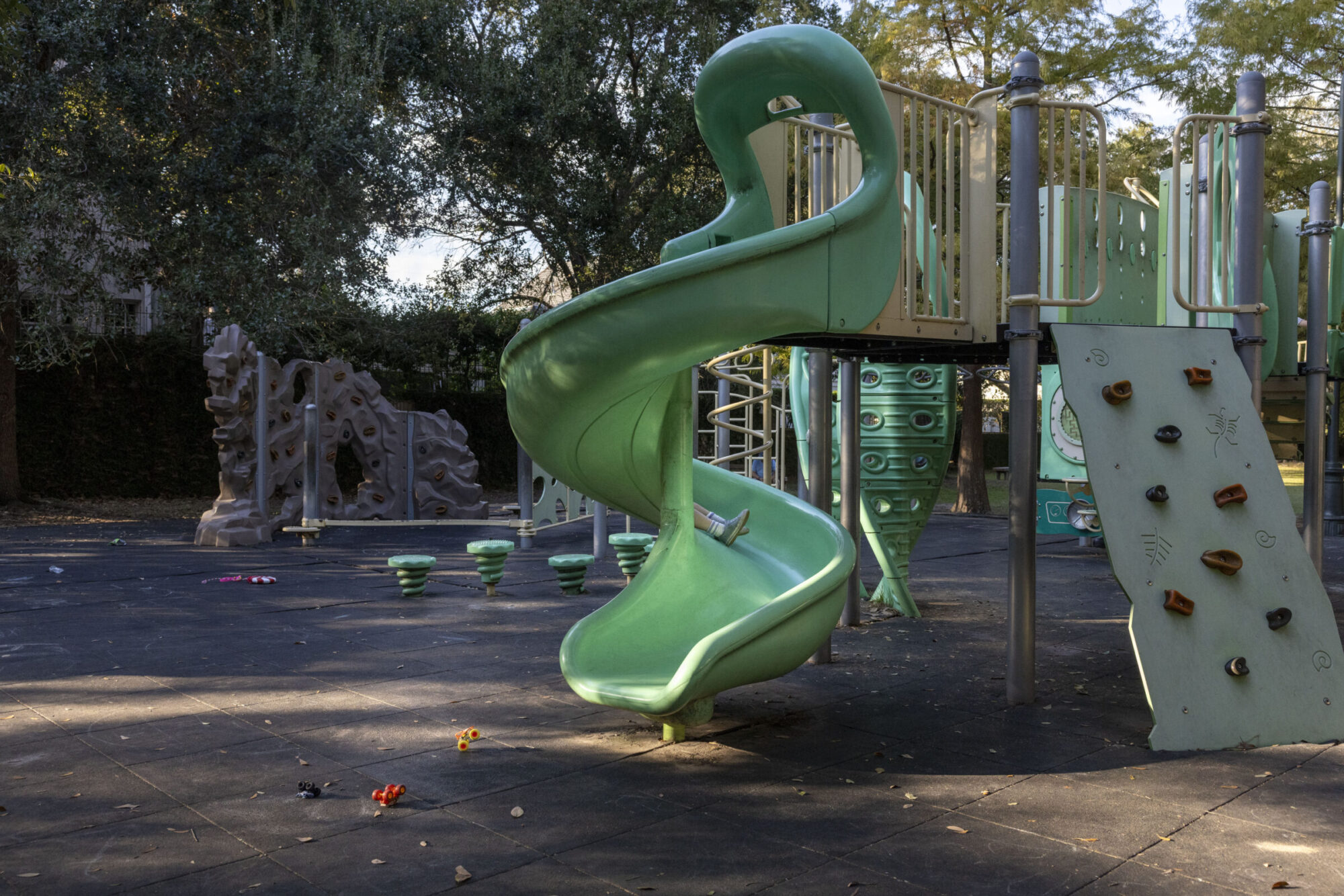 A green twisty slide is seen in a playground