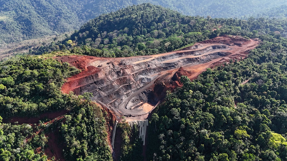 An overhead shot of red and brown soil carved out of green forest