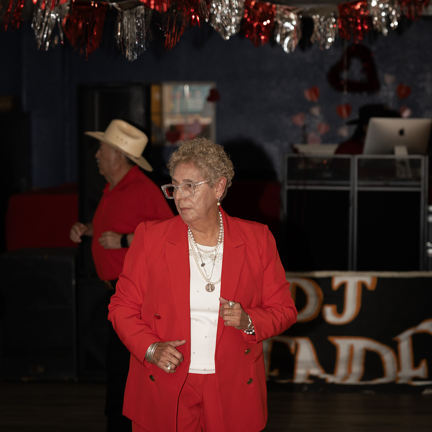 A woman in a red suit on the dance floor in front of the DJ booth