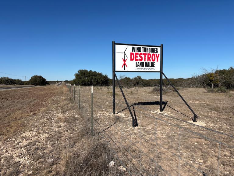 a billboard in a rural area says 'wind turbines destroy land value (among other things)'