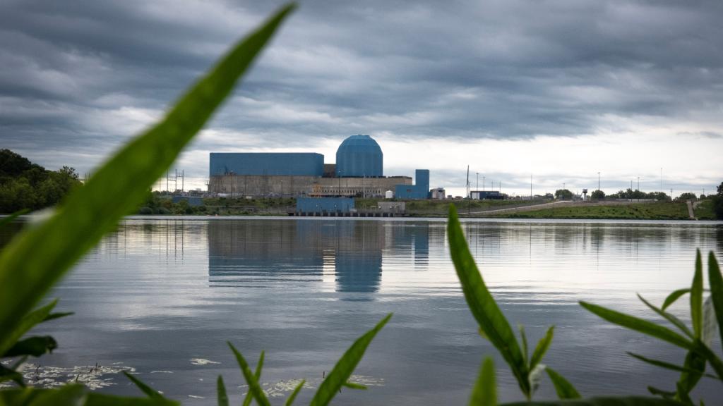 A nuclear plant with blue buildings sits on the edge of a lake