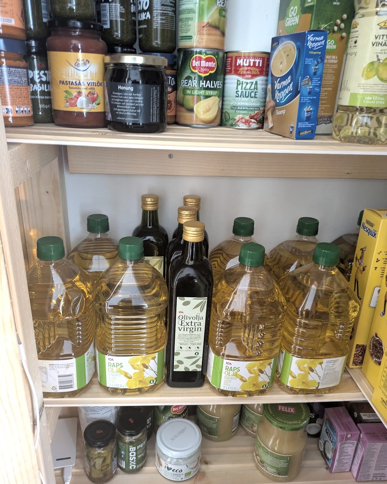 a pantry shelf with canned goods and several bottles of oil