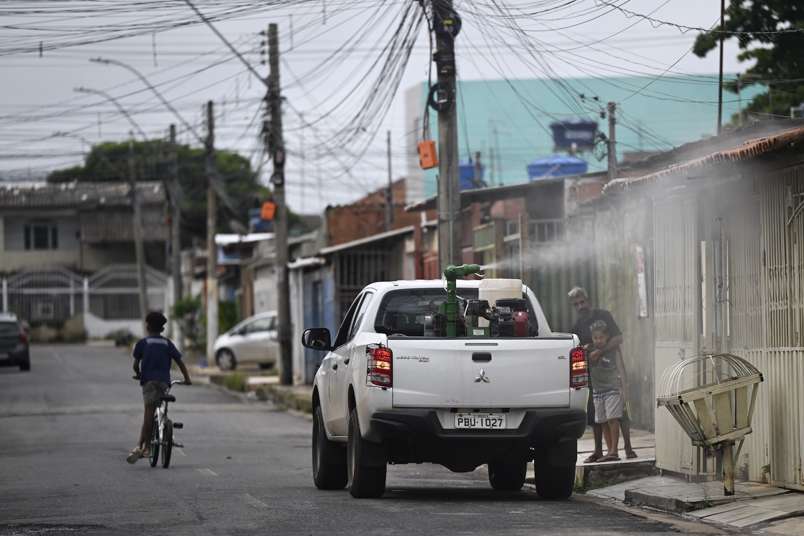 a white truck sprays insecticide in a Brazilian neighborhood