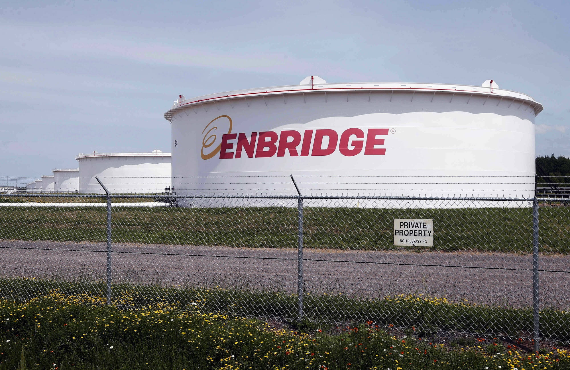 A line of large gas storage tanks that say enbridge on them