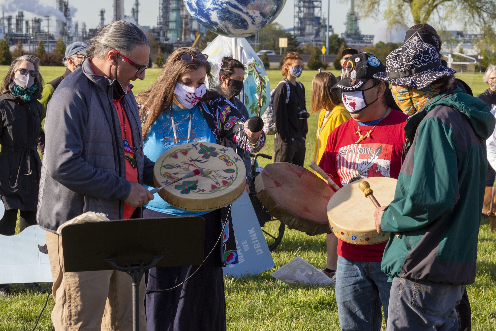 A group of people hold decorated drums pas part of a protest