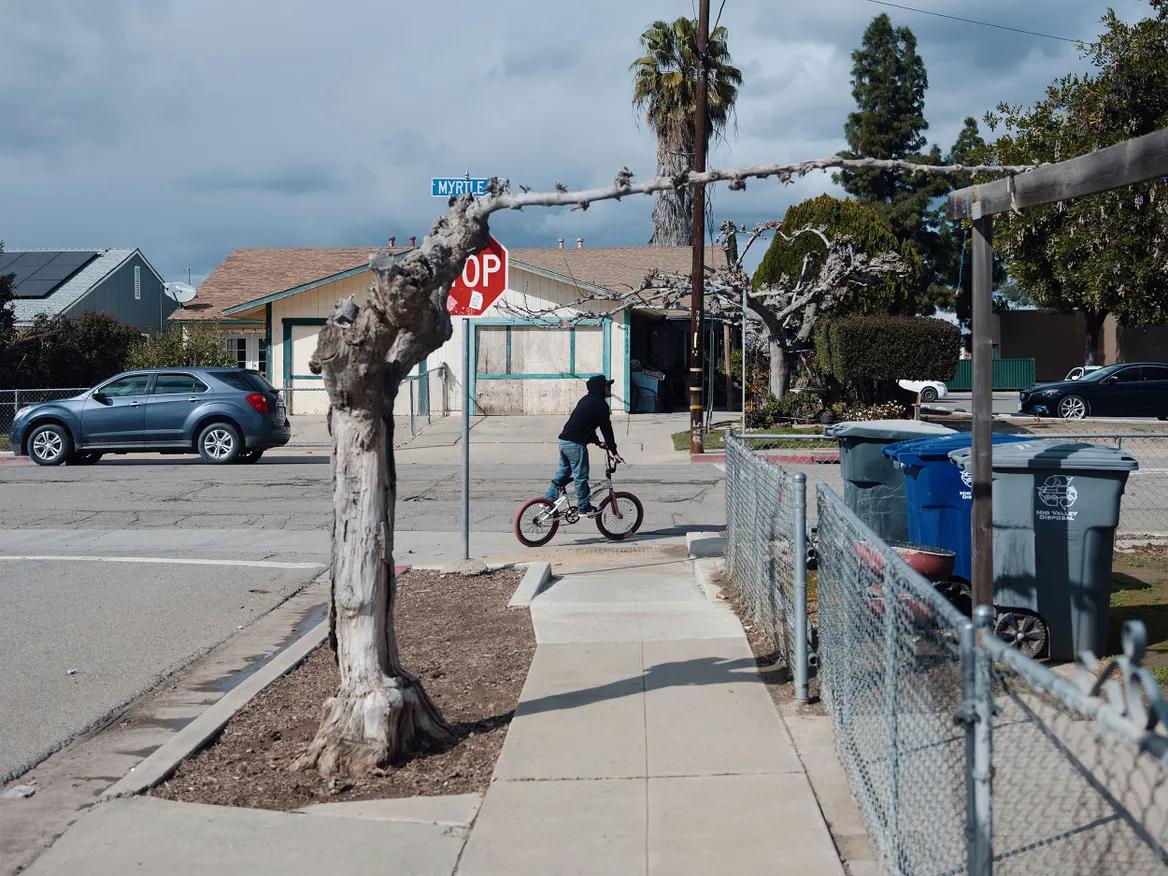 A teen bikes down a California street