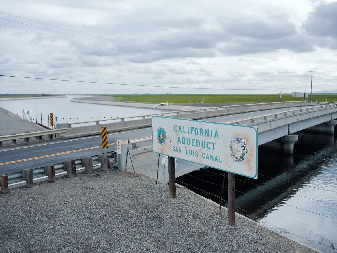 Water cuts through a field with a bridge over it