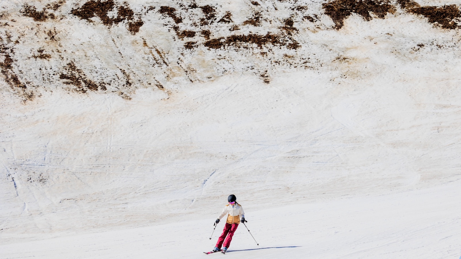 A skier passes by an area of low snow coverage at Vail Ski Resort as temperatures reach into the 50s on March 18, 2026 in Vail, Colorado.