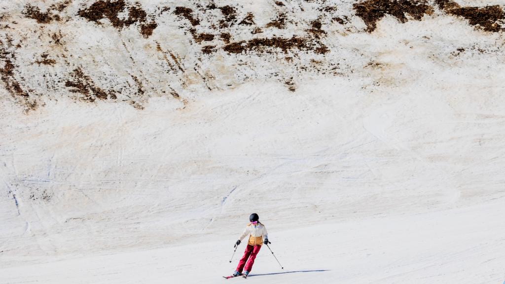 A skier passes by an area of low snow coverage at Vail Ski Resort as temperatures reach into the 50s on March 18, 2026 in Vail, Colorado.
