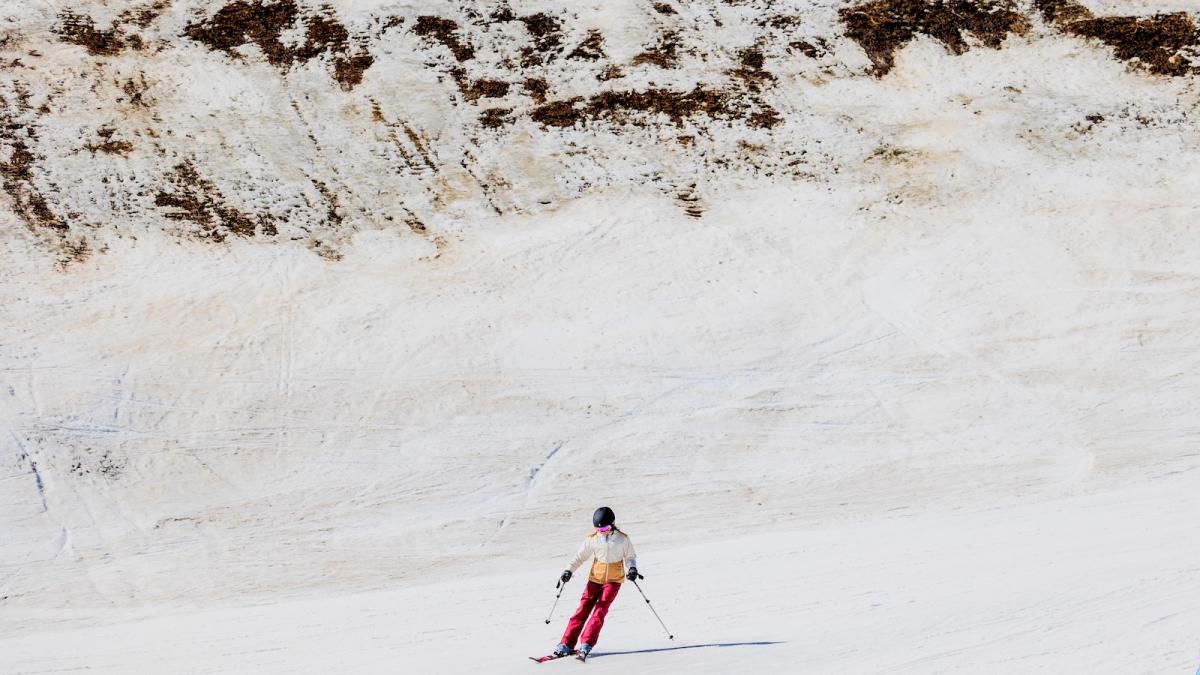 A skier passes by an area of low snow coverage at Vail Ski Resort as temperatures reach into the 50s on March 18, 2026 in Vail, Colorado.