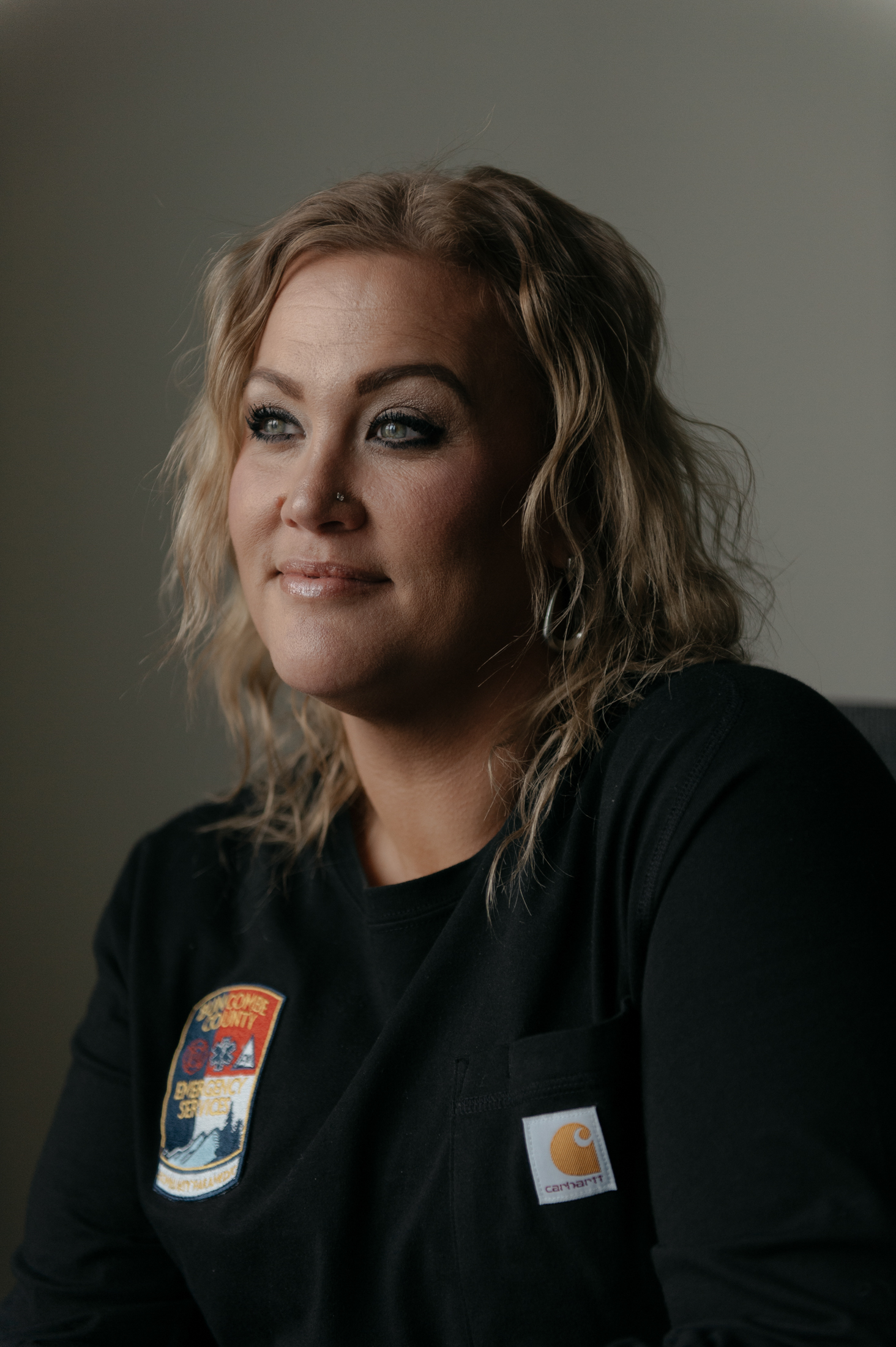 Brandi Hayes looks off screen, wearing a paramedic jacket.