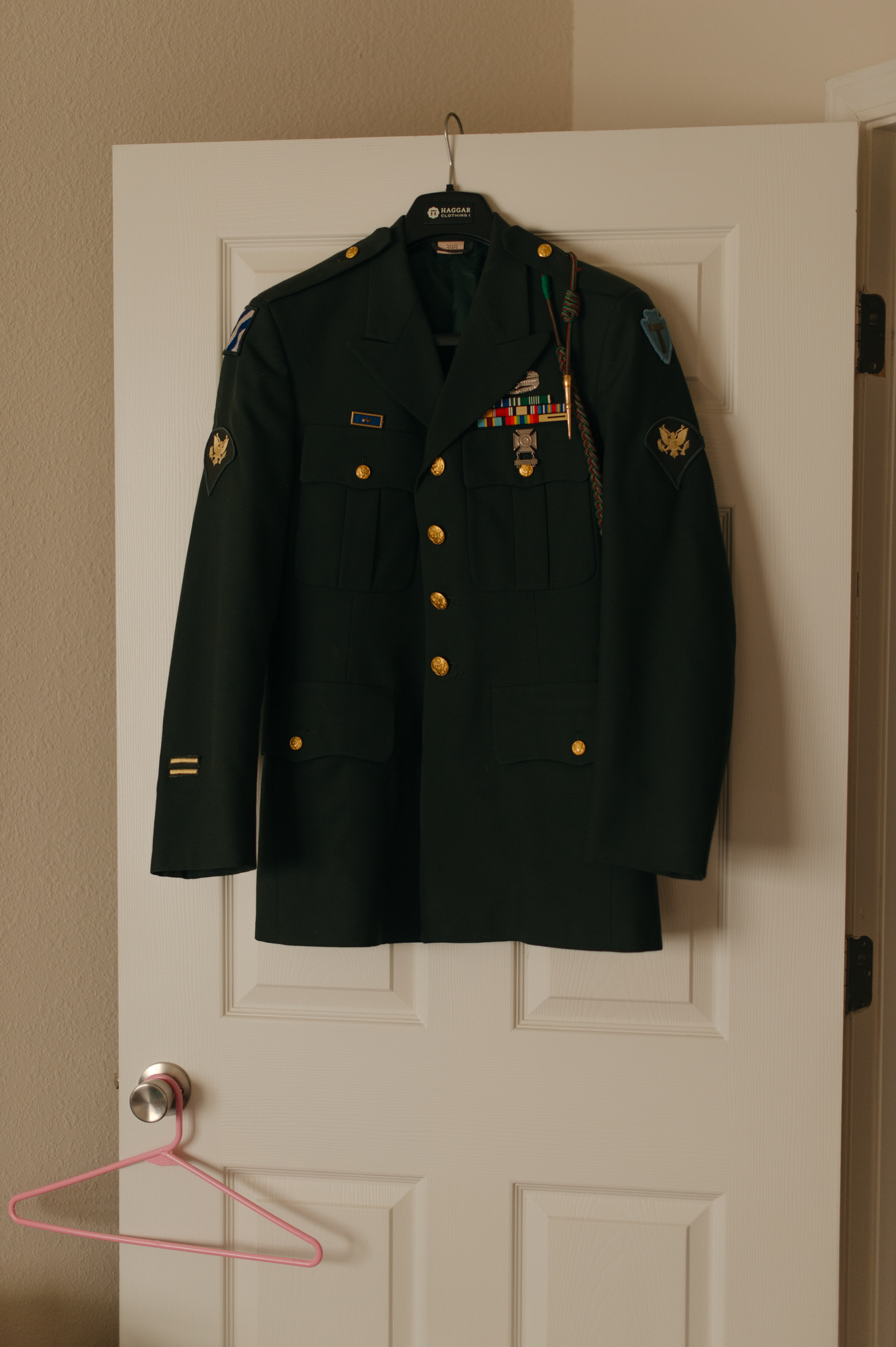 A formal military jacket hands on a door.