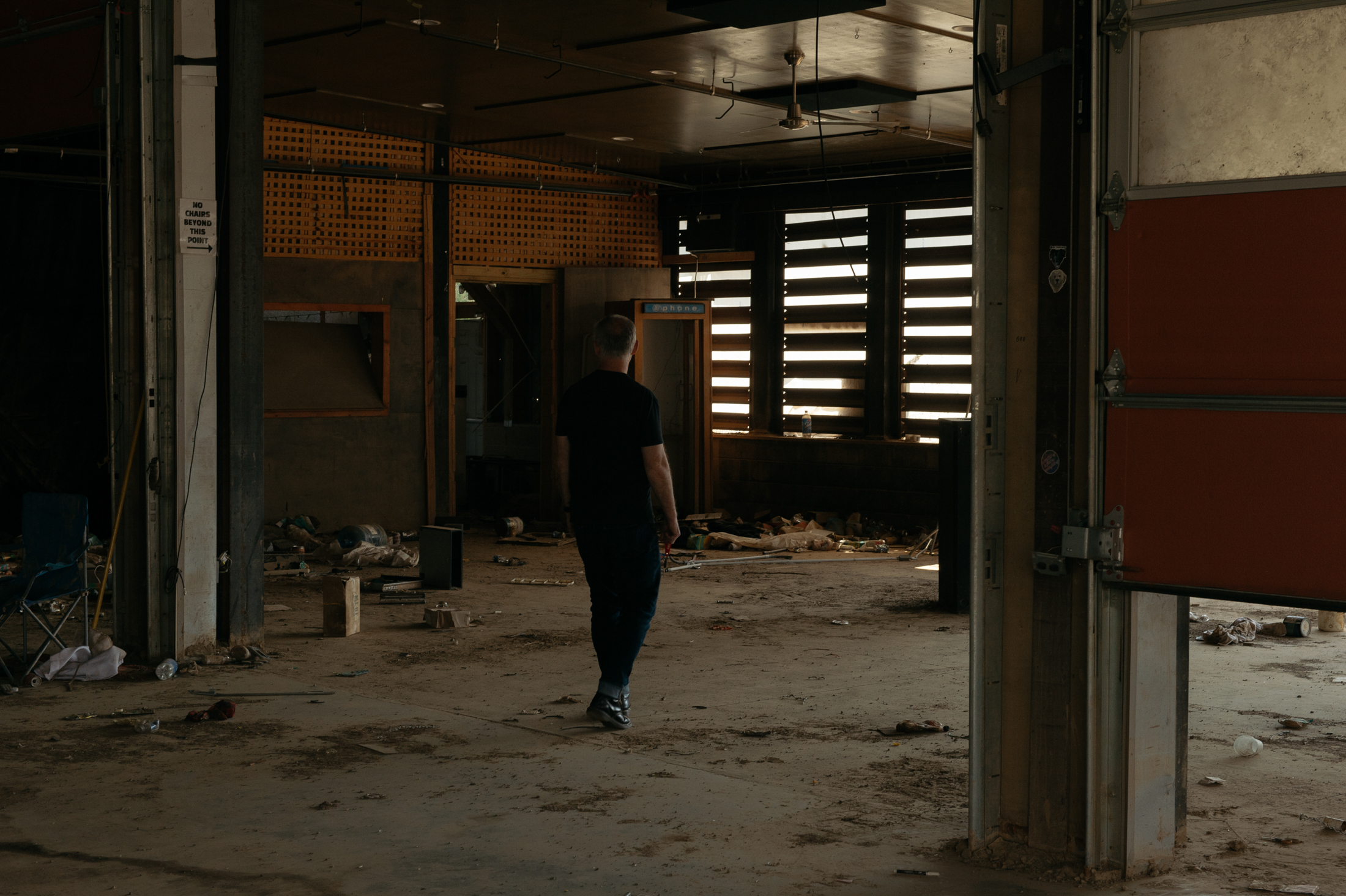 A man walks through a dark, stripped-down building that was once home to a music venue.