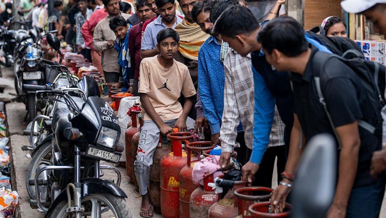 Indian men line up with gas cylinders