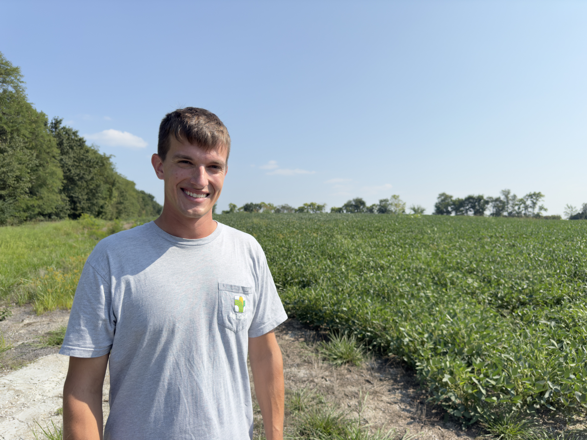 A young man stands in a field of green crops
