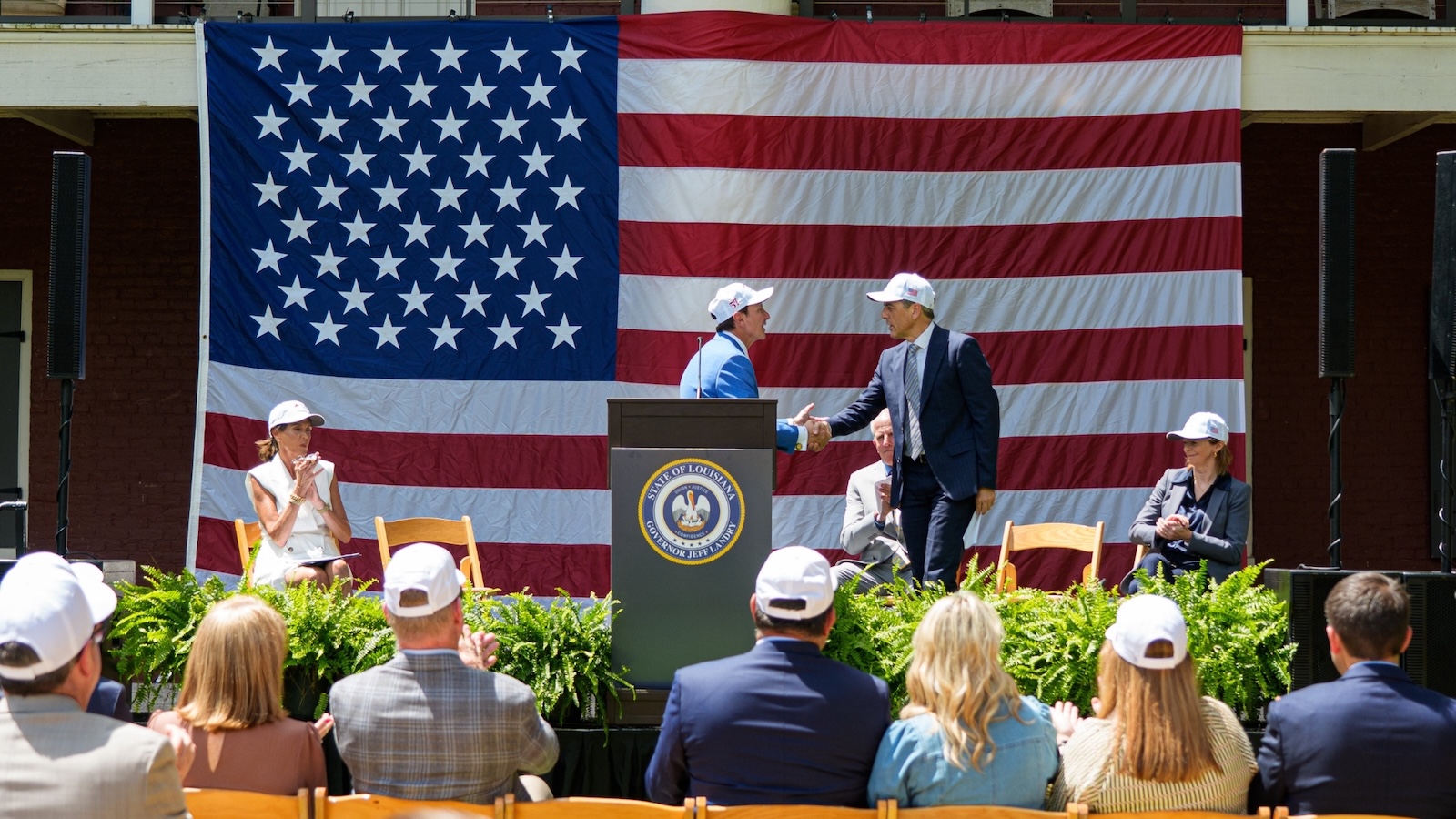 Governor Jeff Landry of Louisiana shakes hands on stage during a ceremony for a planned LNG export terminal.