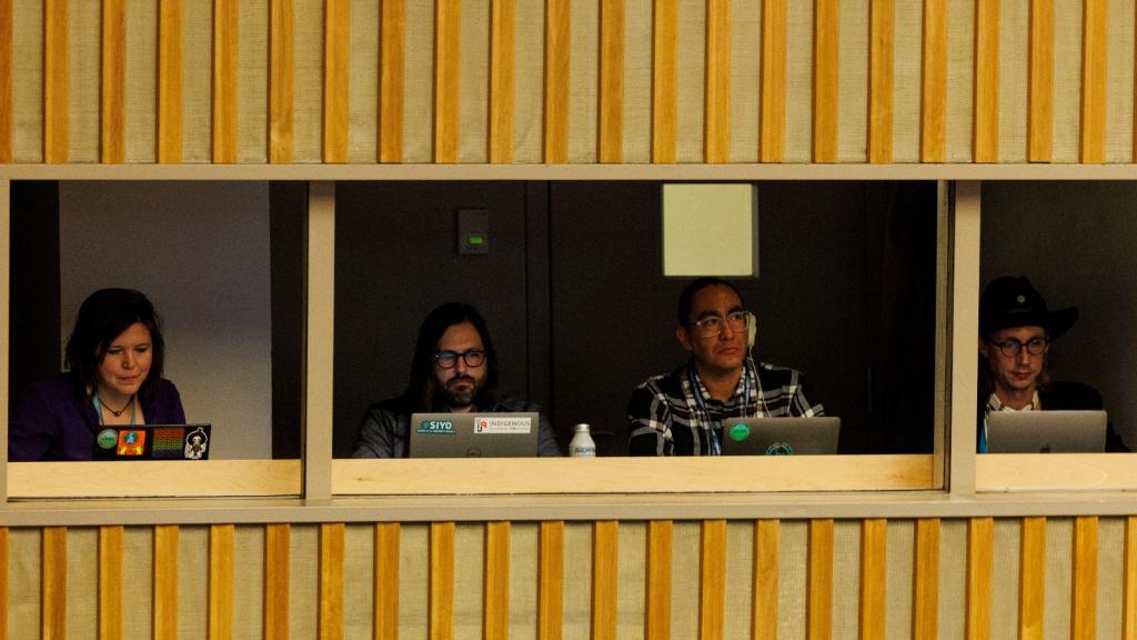 Reporters sit behind laptops in a booth