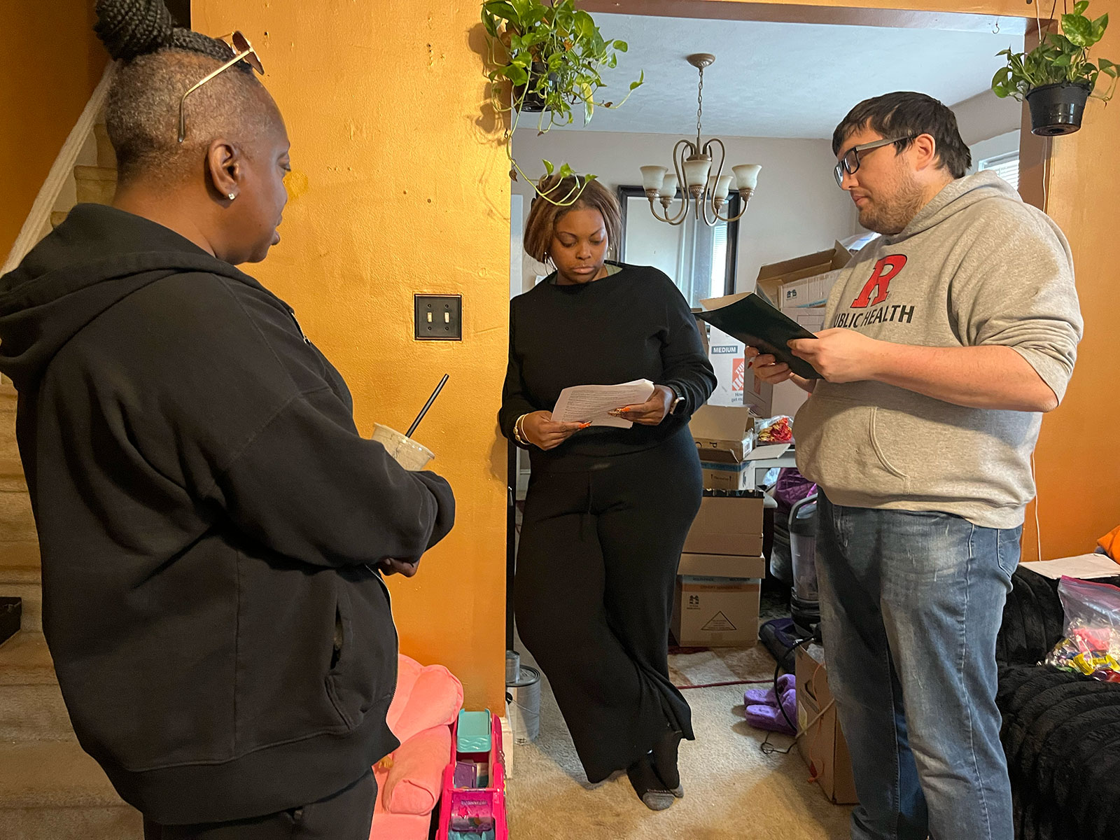 Two women and a man standing in a living room