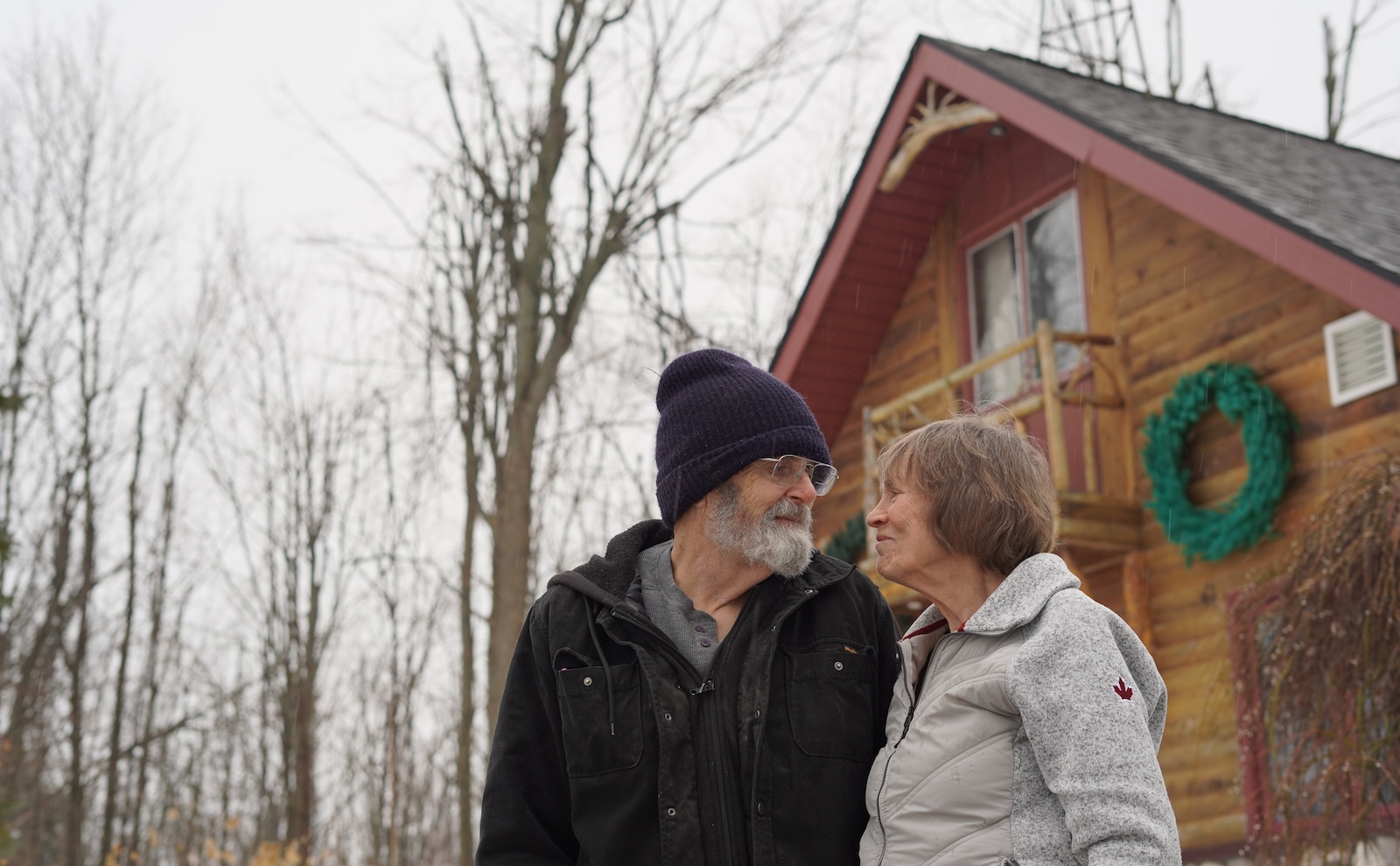 Dave and Wanda Whiting stand outside their home, smiling at each other.