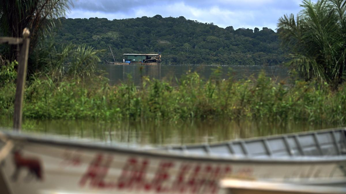 A small boat floats in the foreground on a long river
