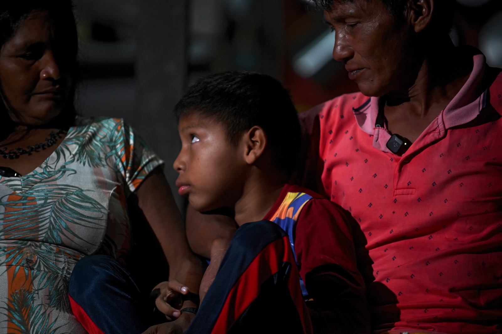 A little boy sits sandwiched between his worried parents