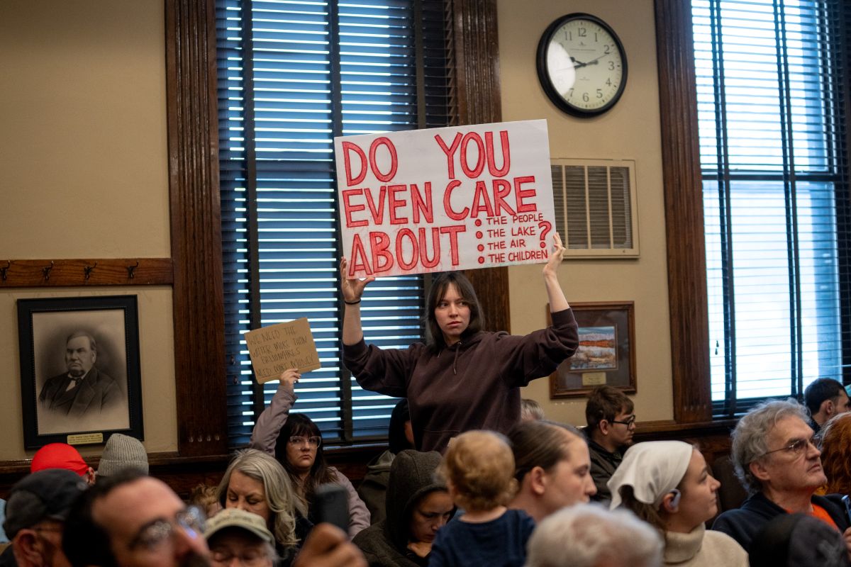 A protestor holds a sign at a meeting