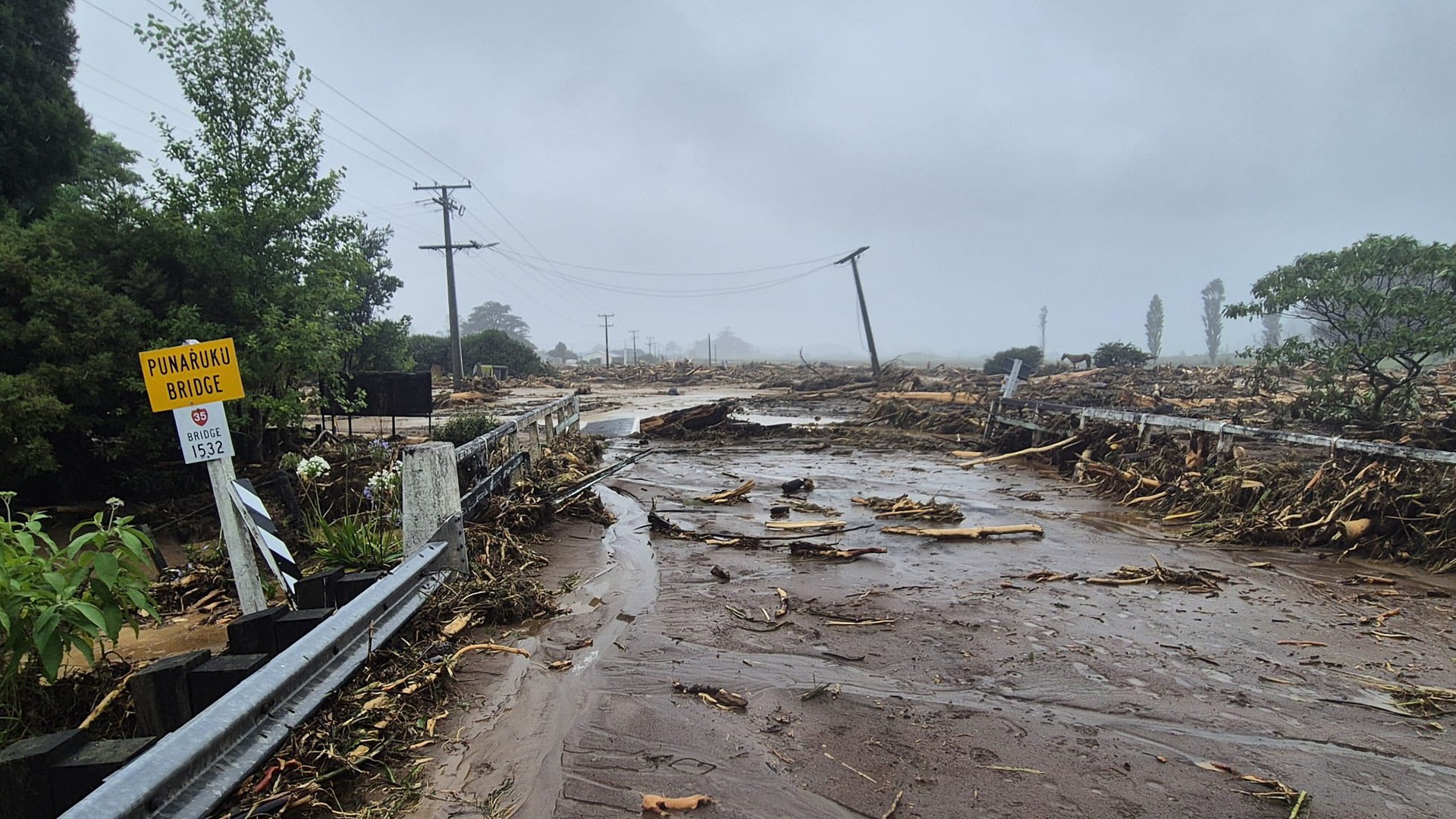 Flooded bridge with mud and tree branches strewn across