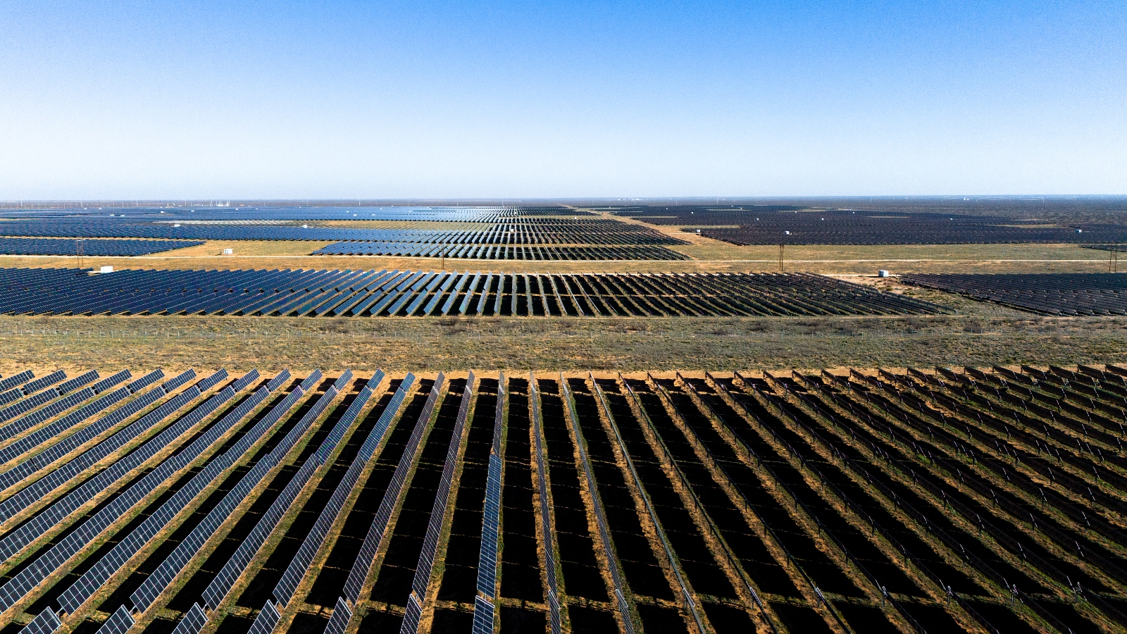 An aerial view of endless black solar panels in a field