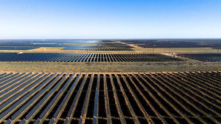 An aerial view of endless black solar panels in a field