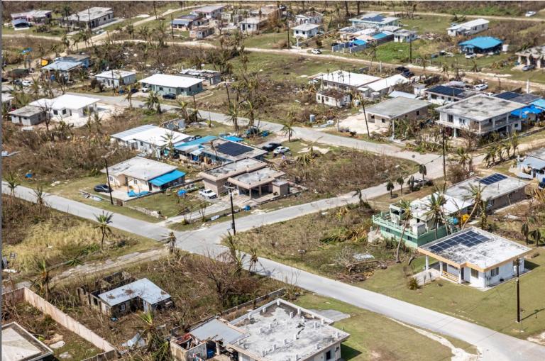 scattered branches, trash, and damaged homes in an aerial photo