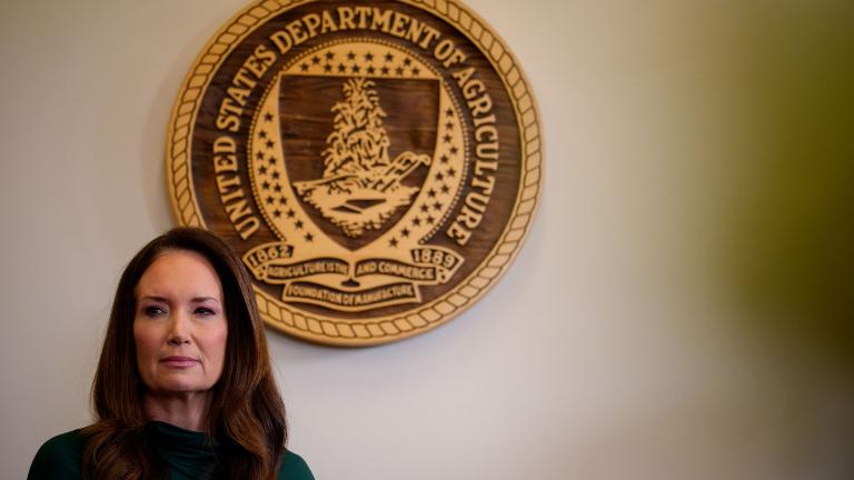 Brooke Rollins standing in front of a wooden seal of the USDA