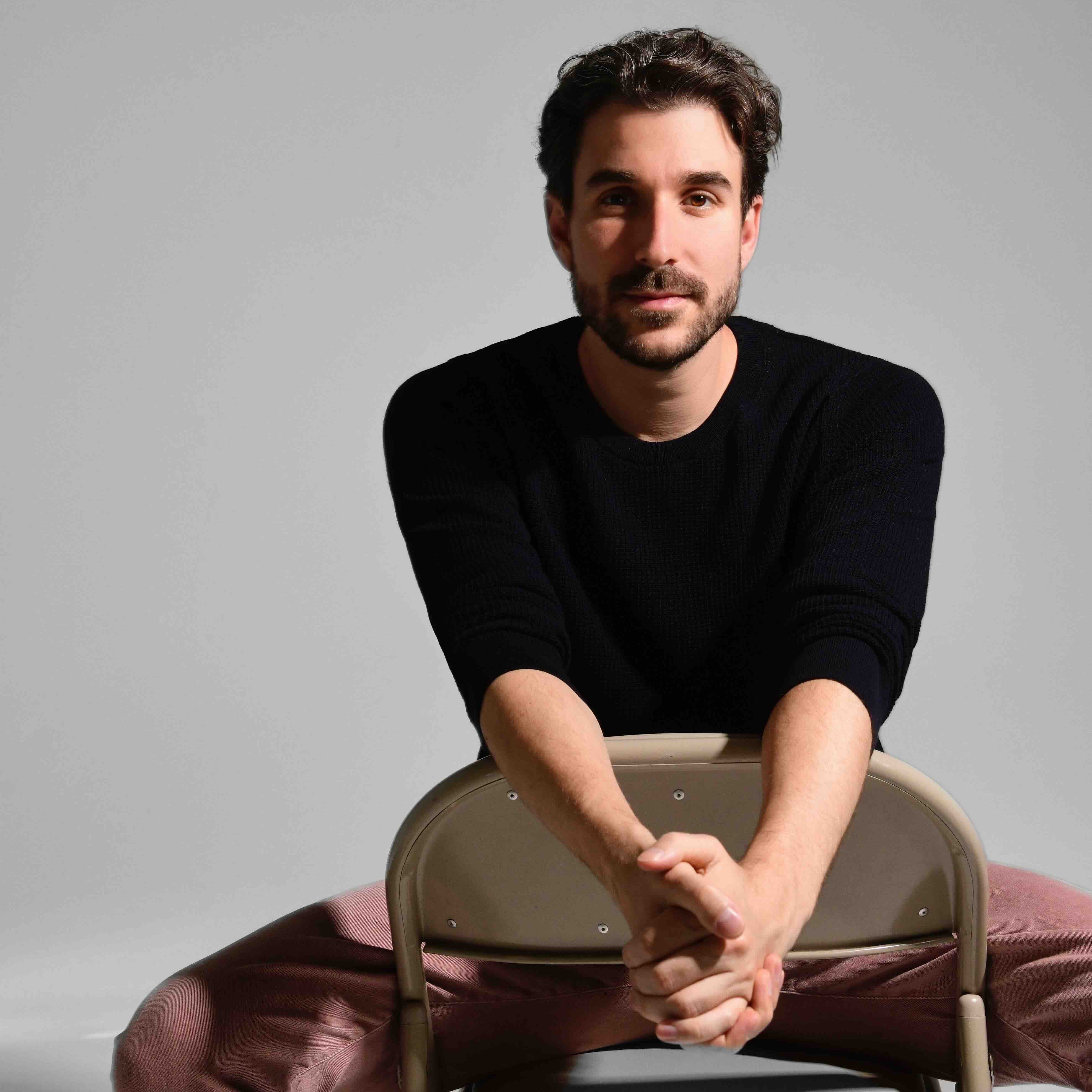 Adam Met sits backward in a chair facing the camera